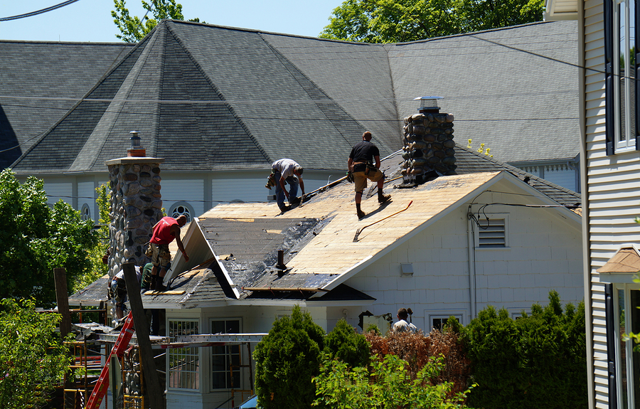 roofers replace the roof on a house