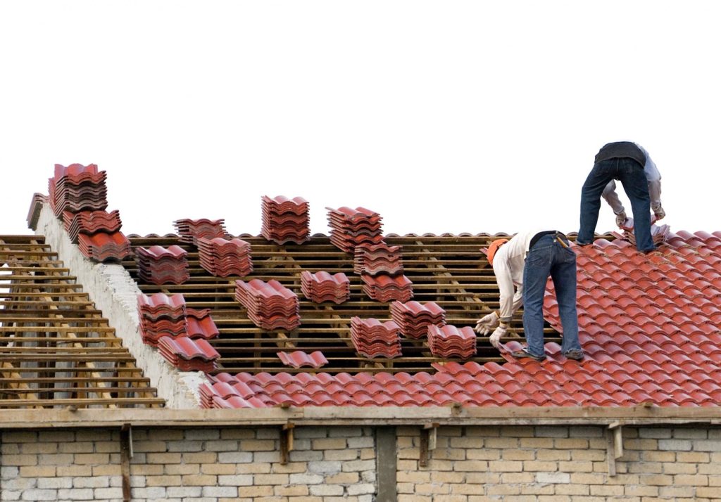 workers are installing house roof tiles