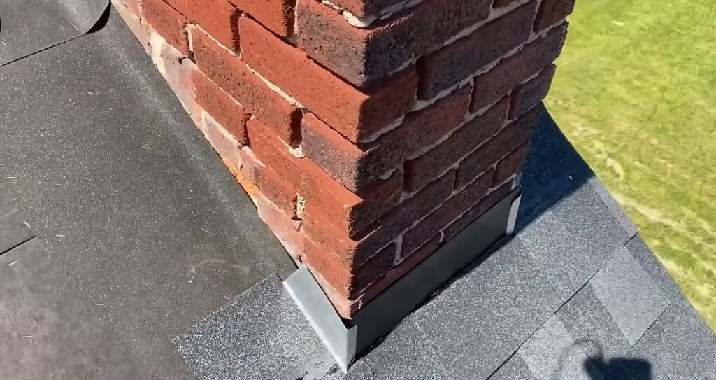 Close-up of new step flashing installed against a brick chimney during a roof inspection in Albuquerque, NM