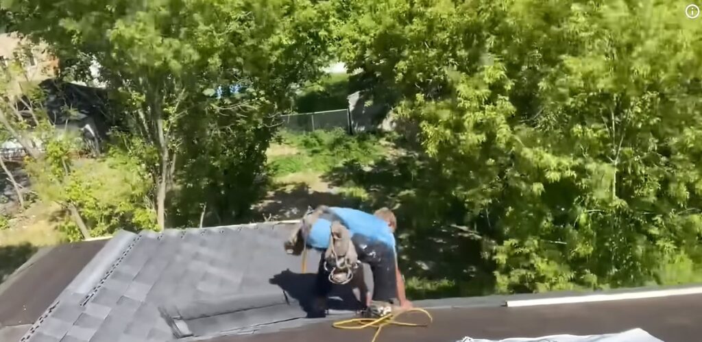 Licensed roofing contractor kneeling on a residential roof installing architectural asphalt shingles in Albuquerque, NM